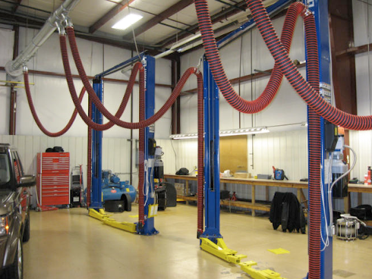 Vehicle exhaust hoses showin installed at an auto repir shop to remove fumes and gas emissions.