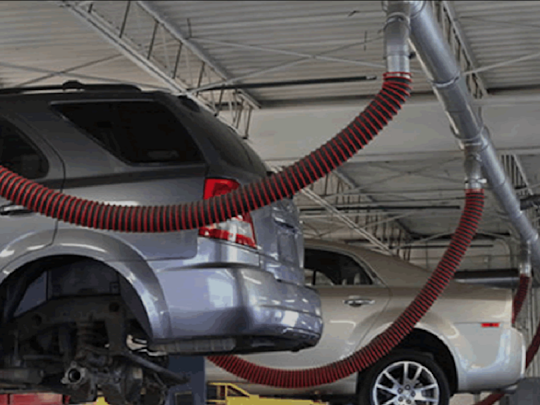 Auto dealership with vehicle on lift and connected to a Fume-A-Vent simple drop system.