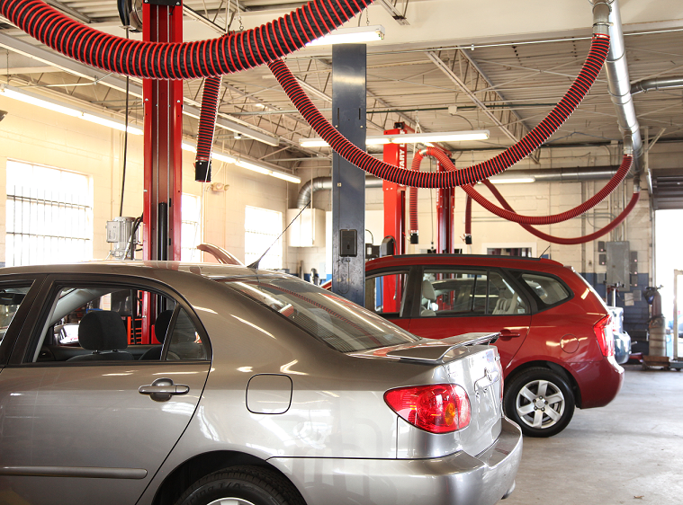 Fume-A-Vent exhaust removal systems installed at an auto dealership to capture and exhaust harmful gas emissions.