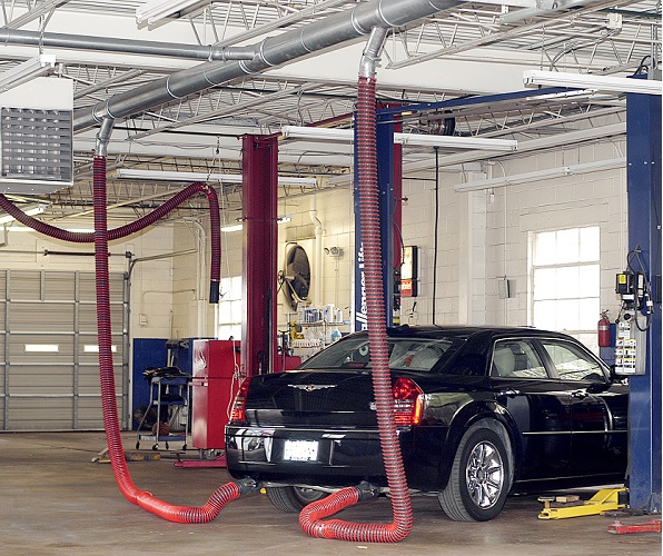 Rope and pulley overhead exhaust removal system installed in a vehicle repair workshop.